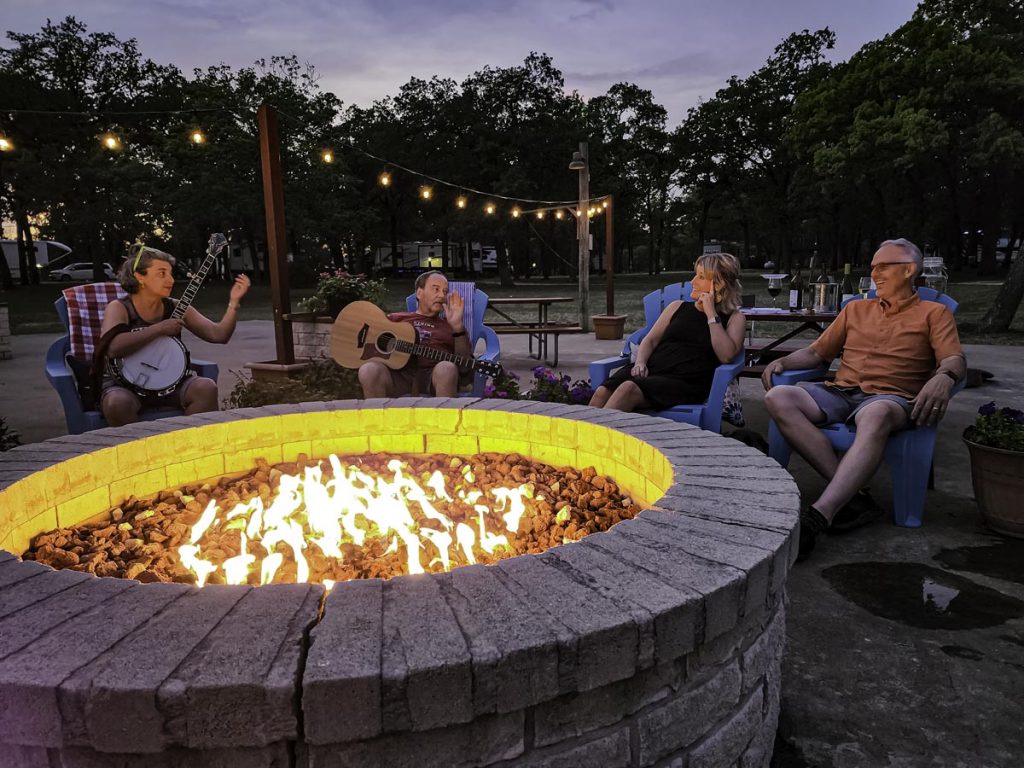 people laughing around a fire pit at dusk