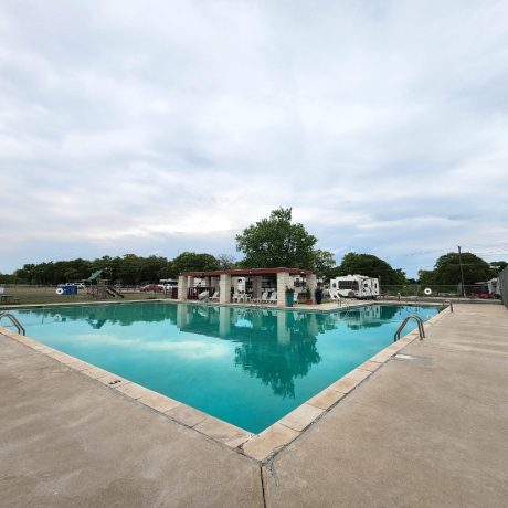 An inviting view of the resort's Olympic-sized swimming pool, emphasizing the relaxation and cooling off options available during hot Texas summers at Oakwood RV Resort in Fredericksburg, TX.