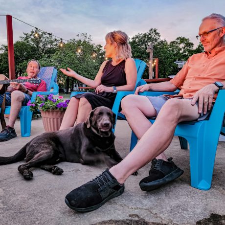 A happy friends singing and playing instruments at Oakwood RV Resort in Fredericksburg, TX, surrounded by beautiful shady views and rustic charm.