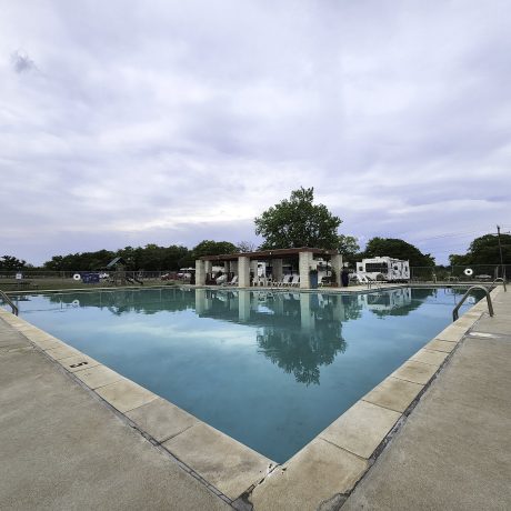 An inviting view of the resort's Olympic-sized swimming pool, emphasizing the relaxation and cooling off options available during hot Texas summers at Oakwood RV Resort in Fredericksburg, TX